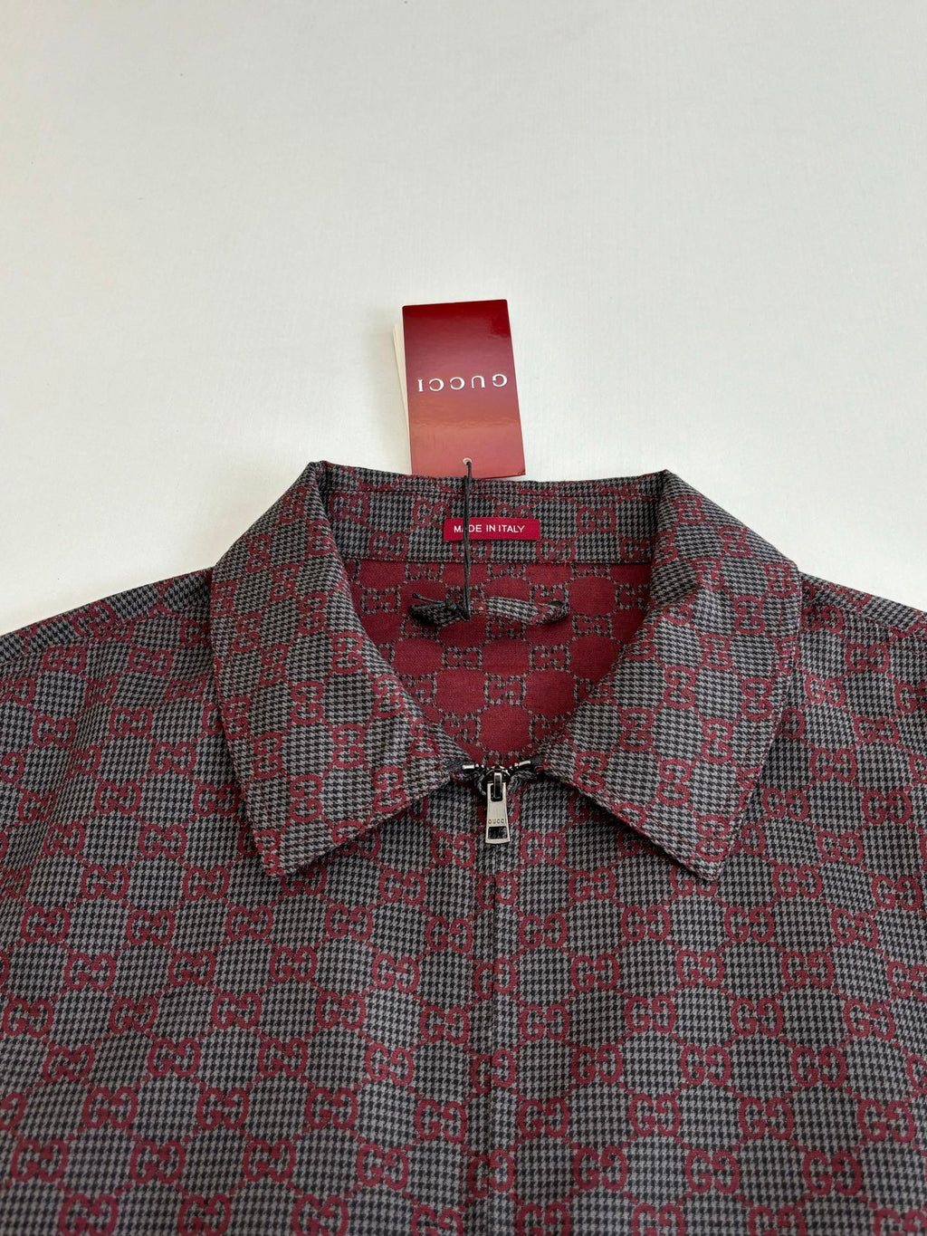 Gucci patterned jacket close-up, buttoned collar and zip placket in maroon and dark.