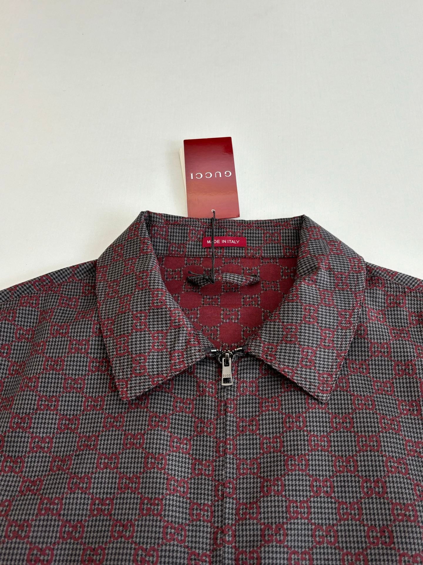 Gucci patterned jacket close-up, buttoned collar and zip placket in maroon and dark.