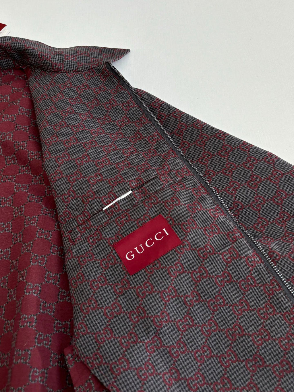 Gucci logo patch on patterned zip jacket, maroon and dark with buttoned collar.