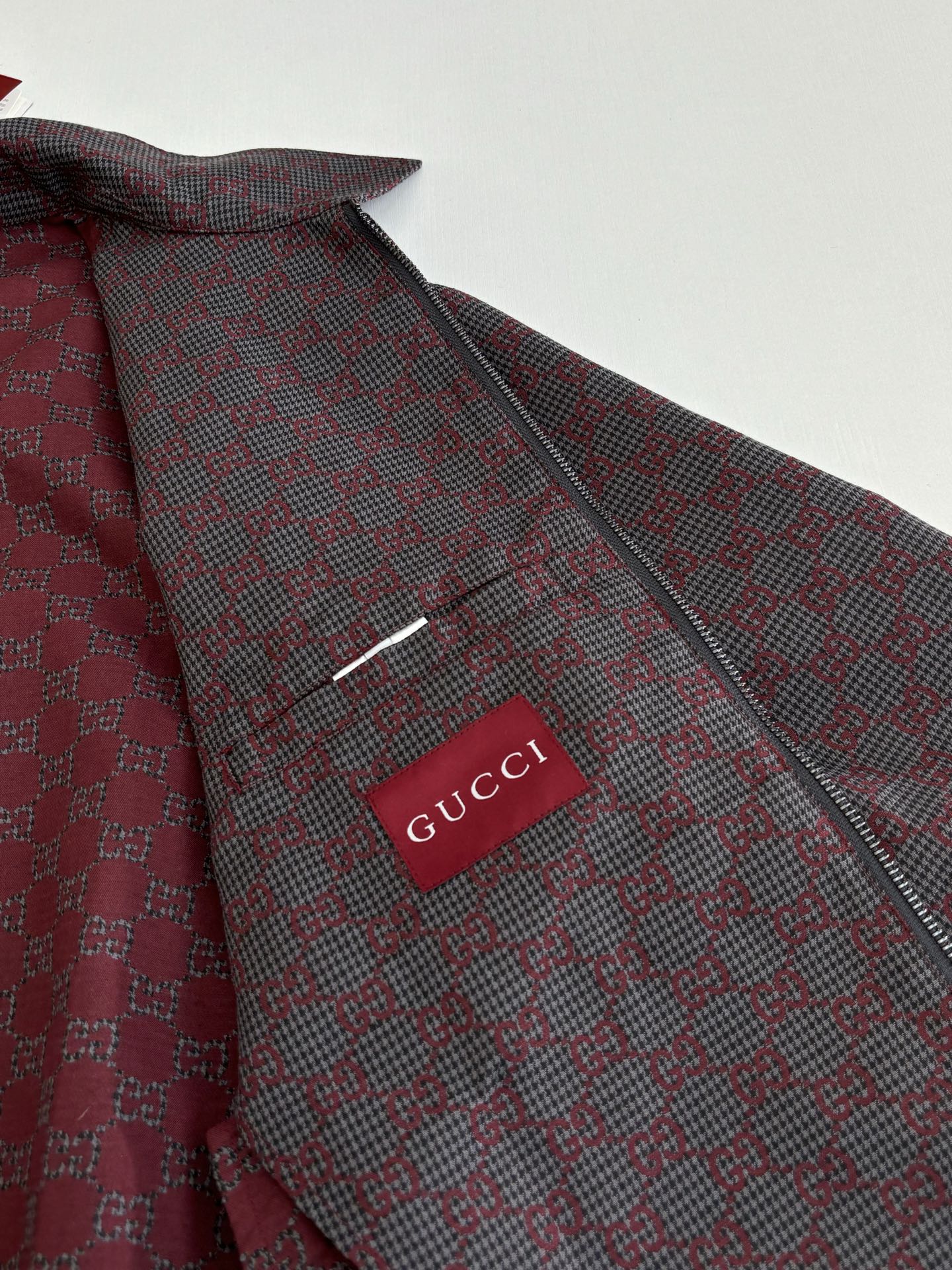Gucci logo patch on patterned zip jacket, maroon and dark with buttoned collar.