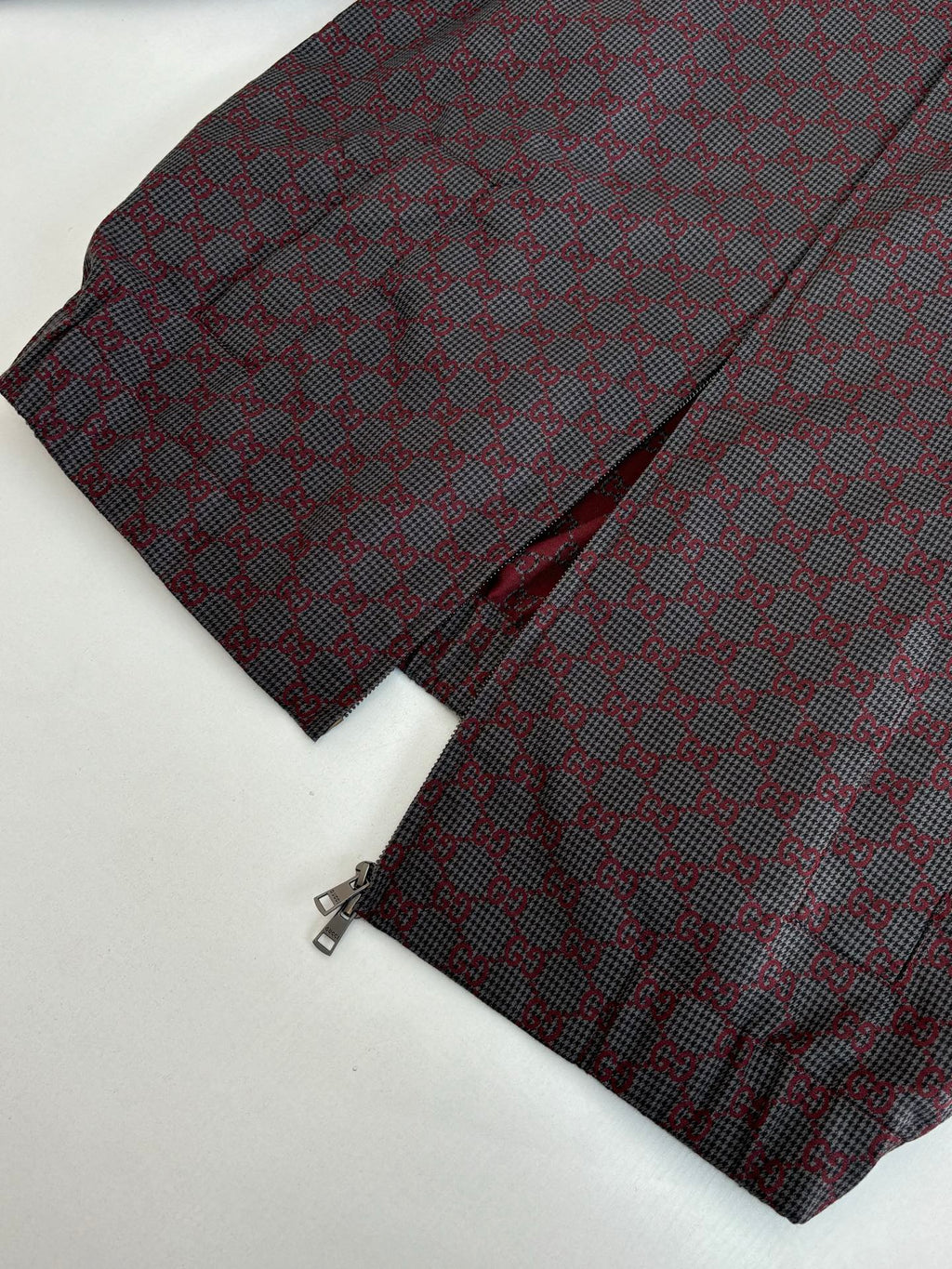 Gucci jacket sleeve and pants folded together, maroon and dark patterned fabric.