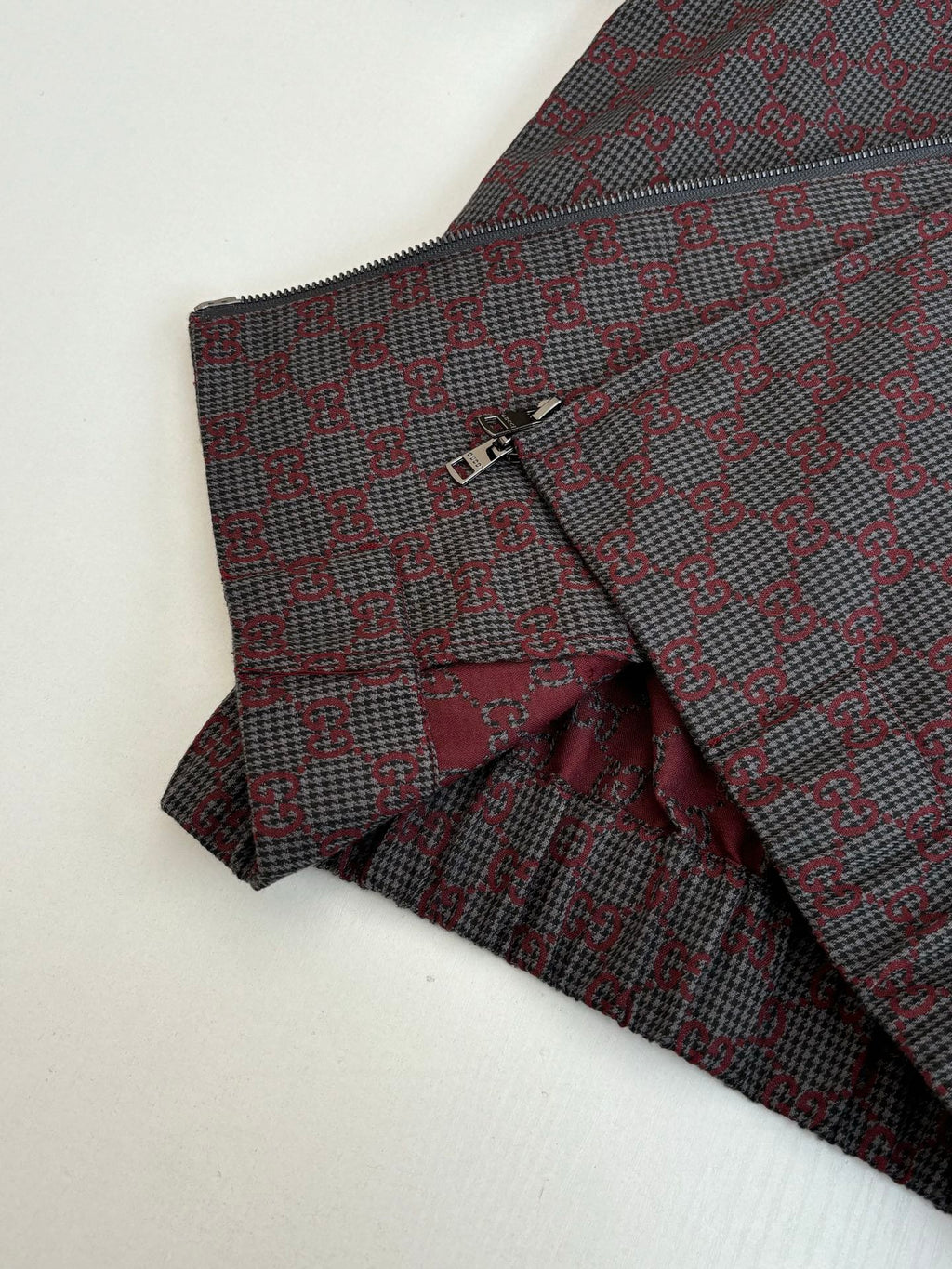 Gucci pants front and jacket detail, maroon and dark patterned fabric with button closure.