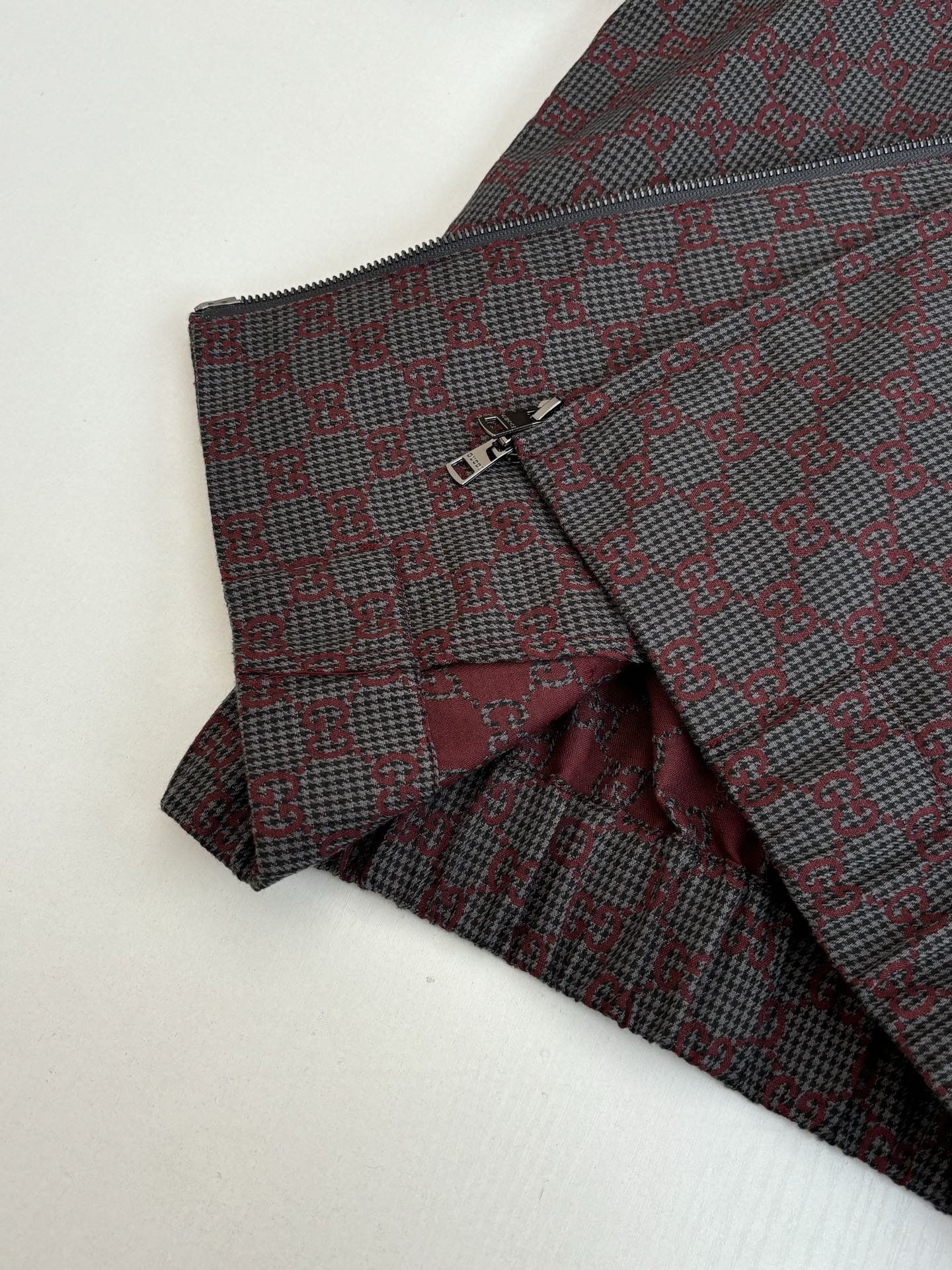 Gucci pants front and jacket detail, maroon and dark patterned fabric with button closure.