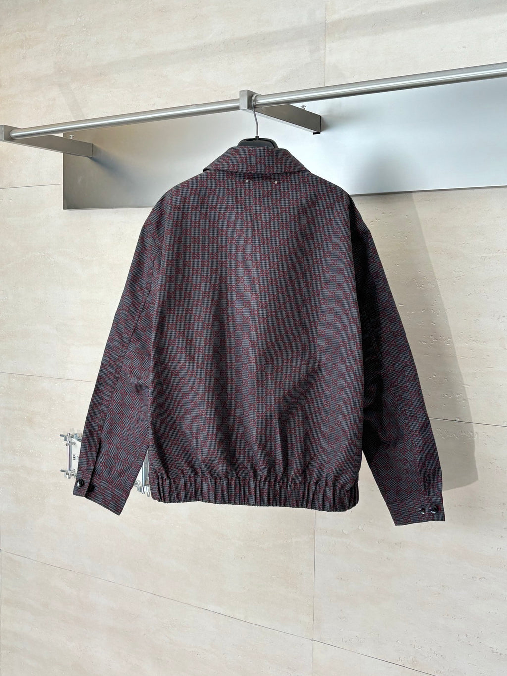 Gucci jacket back on hanger, maroon and dark allover pattern, zip-front and elastic hem.