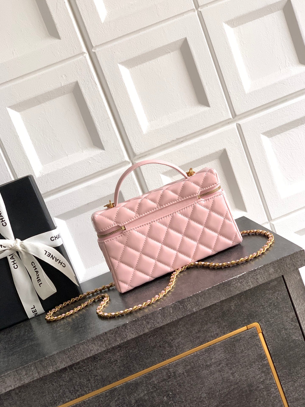 Light pink quilted bag with top handle and gold-tone chain strap, front flap and logo