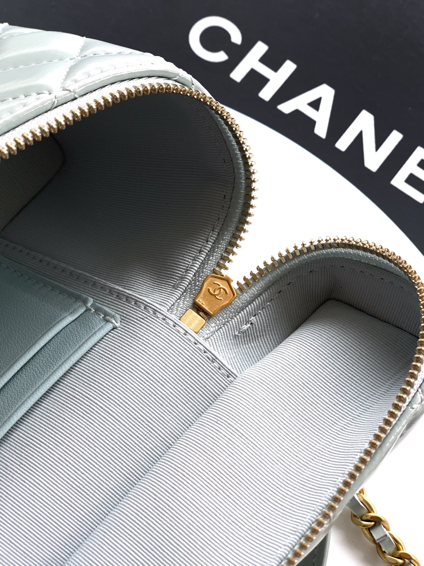 Light blue Chanel bag interior with gold zipper and logo pull tab