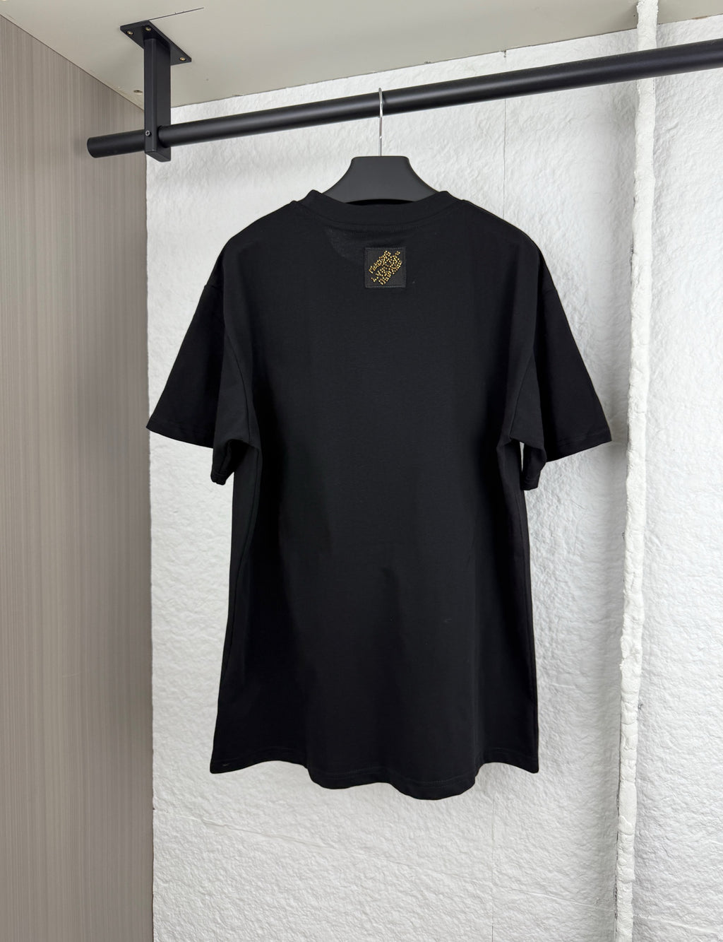 Louis Vuitton black short-sleeve T-shirt, back view with small gold emblem at center collar