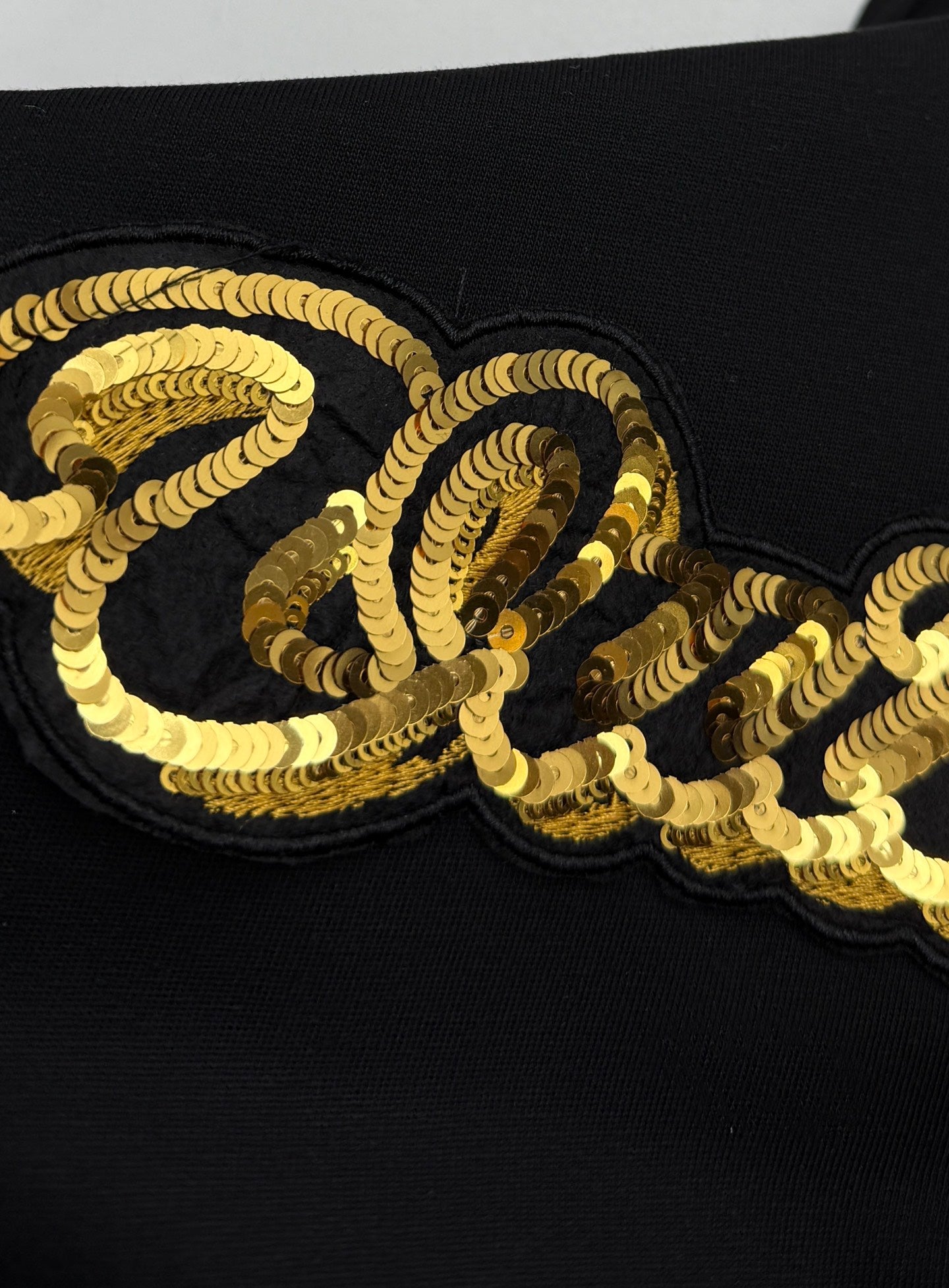 Louis Vuitton black T-shirt with gold sequin-style “Quiltn” graphic detail on chest