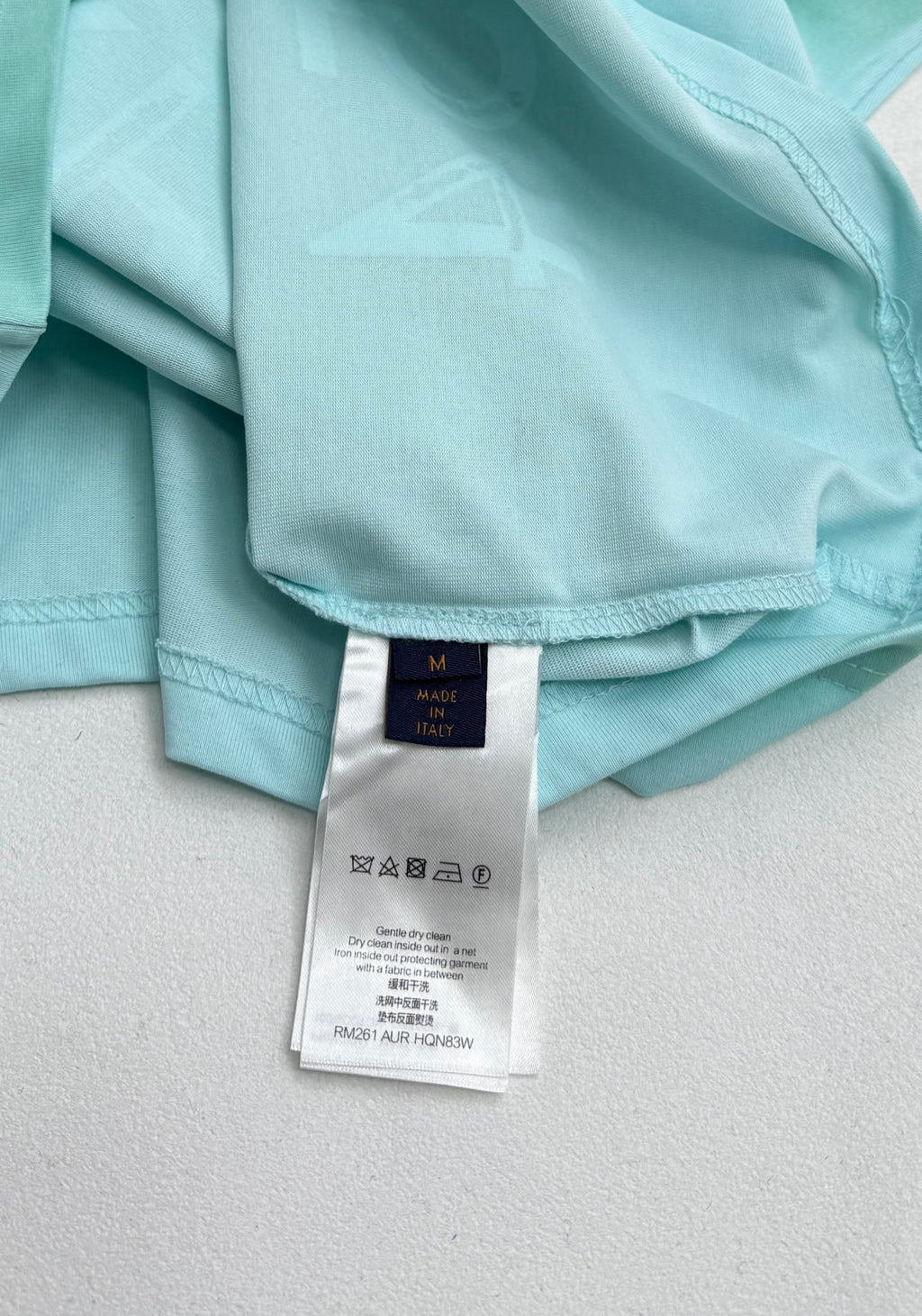Louis Vuitton T-shirt care label on light turquoise inside neck opening.