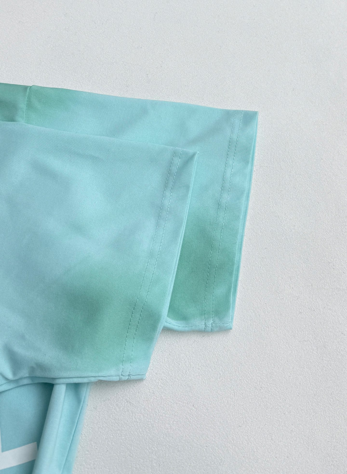 Louis Vuitton T-shirt sleeve and hem in light turquoise, stitched detail.