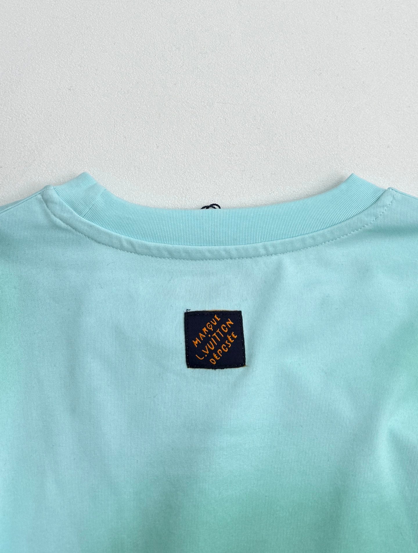 Louis Vuitton T-shirt back neckline in light turquoise with small logo label.