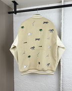 Beige jacket back with scattered animal and palm tree embroidery; ribbed hem and cuffs.