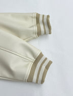 Cream jacket sleeve cuff and hem with striped rib knit trim.