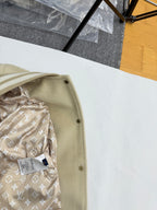 Beige jacket edge with snap buttons and patterned inner lining with LV-style motifs.