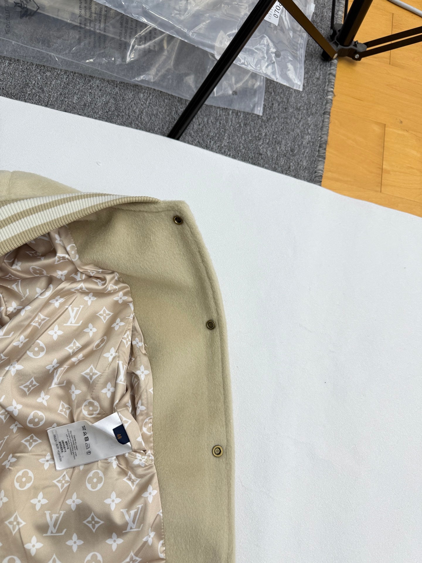 Beige jacket edge with snap buttons and patterned inner lining with LV-style motifs.