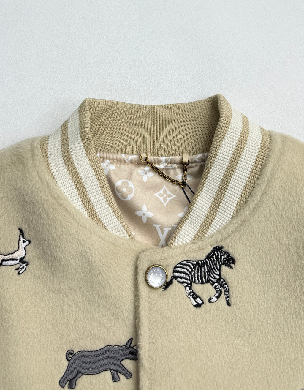 Beige knit jacket collar with striped ribbing and zebra patch detail near button placket.