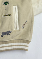 Beige sleeve with animal embroidery and a pocket; striped ribbed cuff and hem trim.