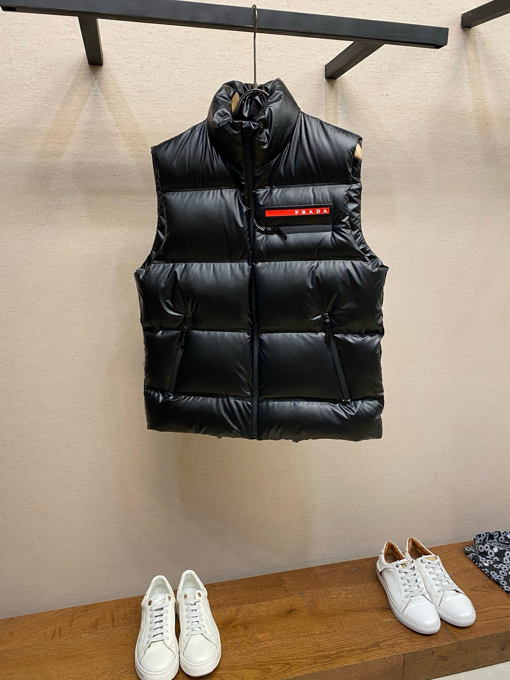 Black puffer vest with hood and central PRADA logo patch.