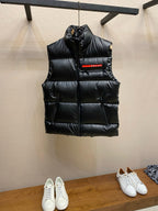 Black puffer vest with hood and central PRADA logo patch.