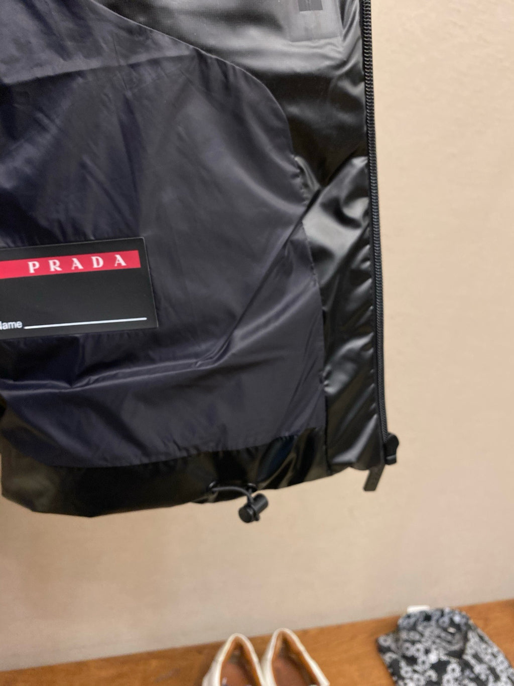 Black sleeveless puffer vest with PRADA label pocket and zipper trim.