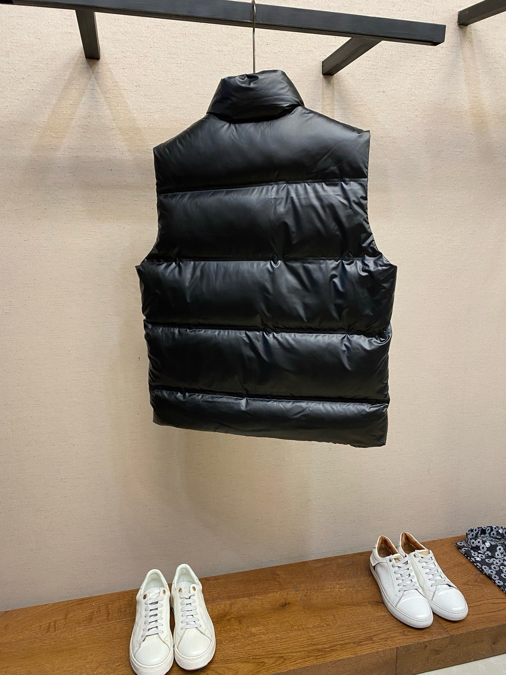 Black sleeveless puffer vest with horizontal quilting, back view.