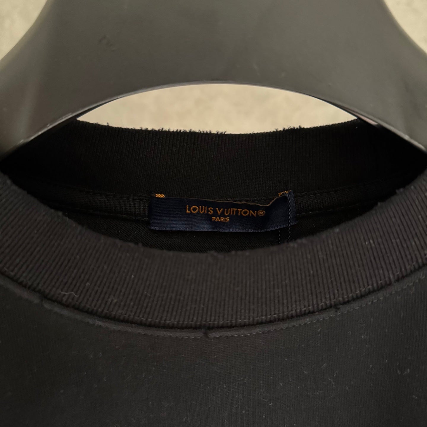 Black T-shirt collar with Louis Vuitton Paris brand label.