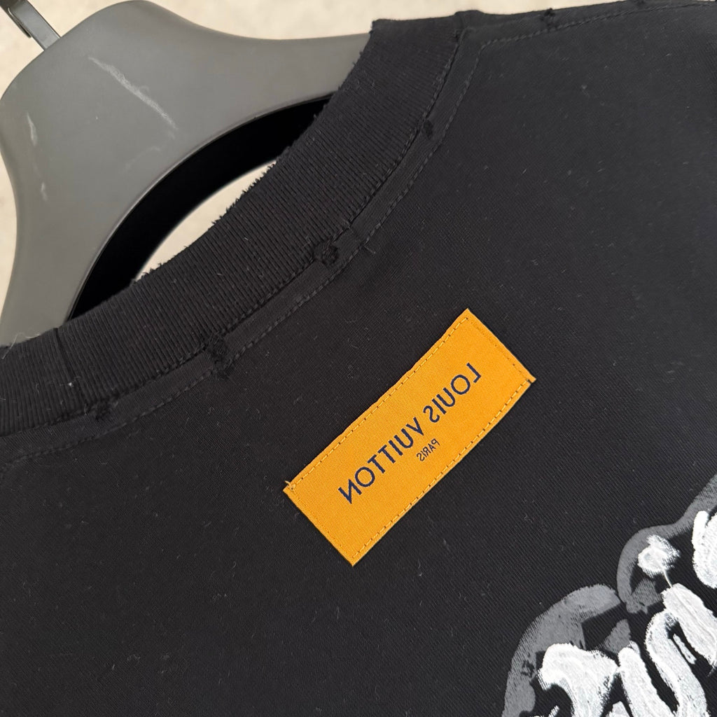 Black T-shirt hem with yellow label and stitched side seam detail.