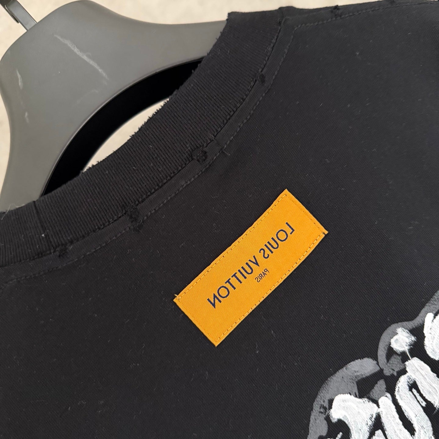 Black T-shirt hem with yellow label and stitched side seam detail.