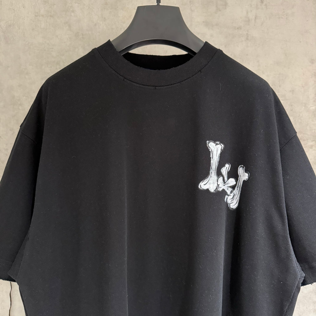 Black T-shirt neckline with small white graffiti-style graphic on chest.