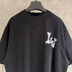 Black T-shirt neckline with small white graffiti-style graphic on chest.