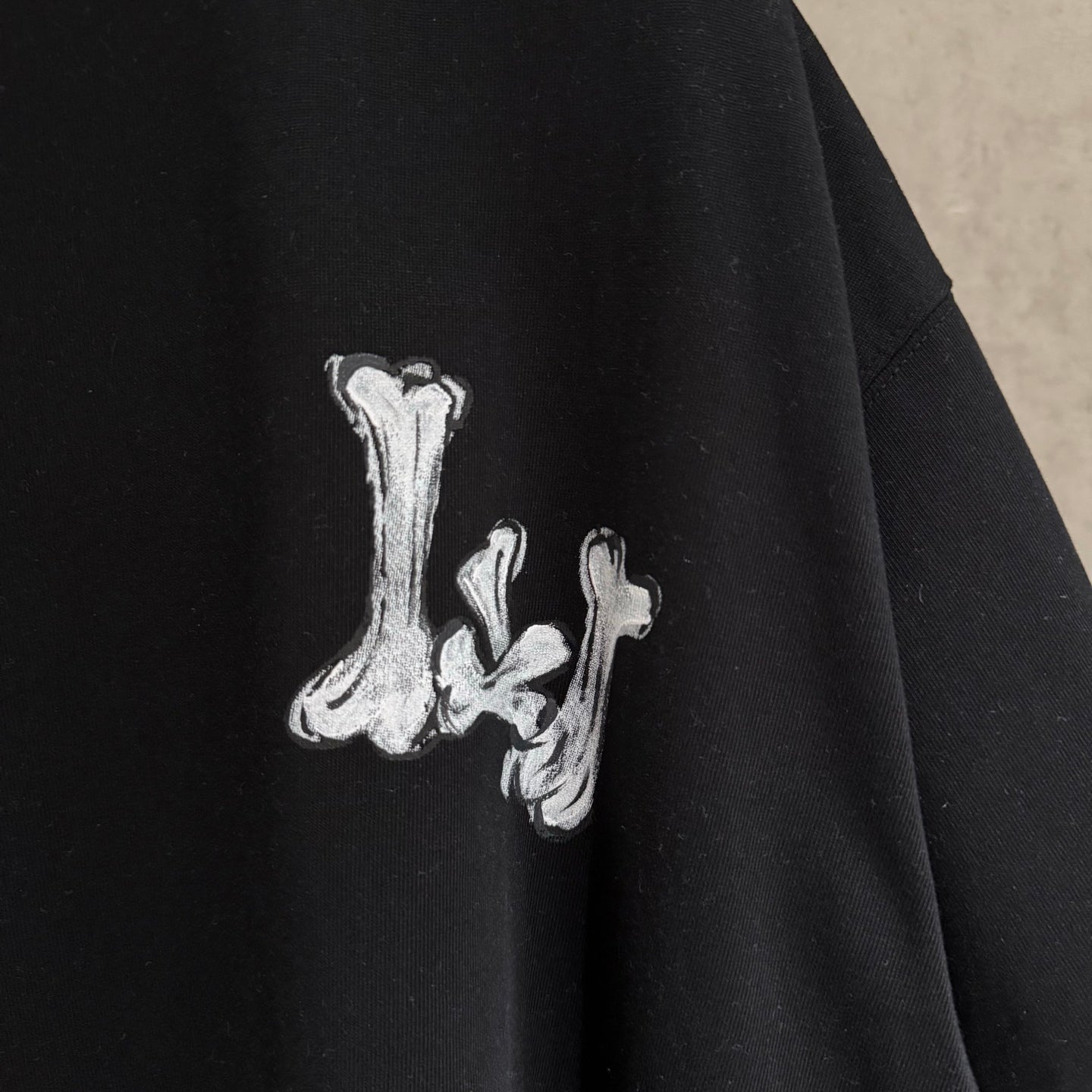 Black T-shirt sleeve with small white graffiti-style graphic.
