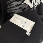 Black T-shirt with white fabric care and size label on inner seam.
