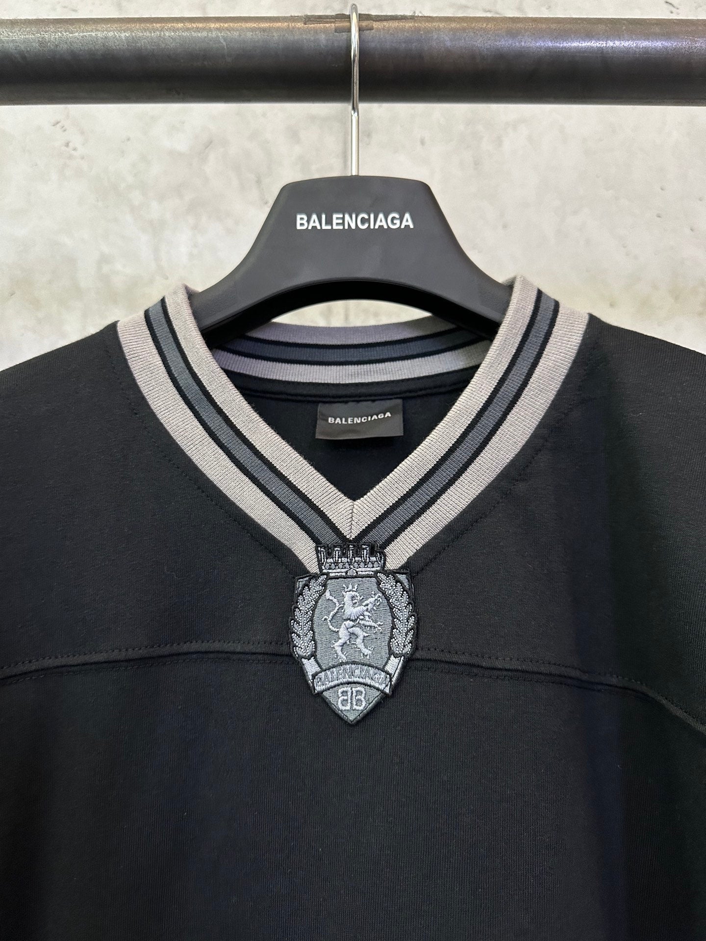 Black Balenciaga long-sleeve top neckline with striped trim and decorative crest
