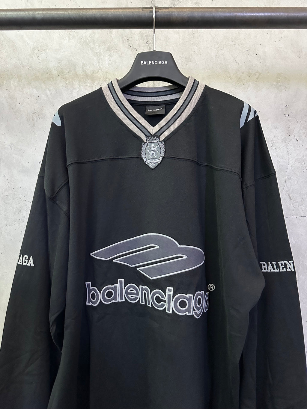 Black Balenciaga long-sleeve top with striped V-neck collar and front logo emblem