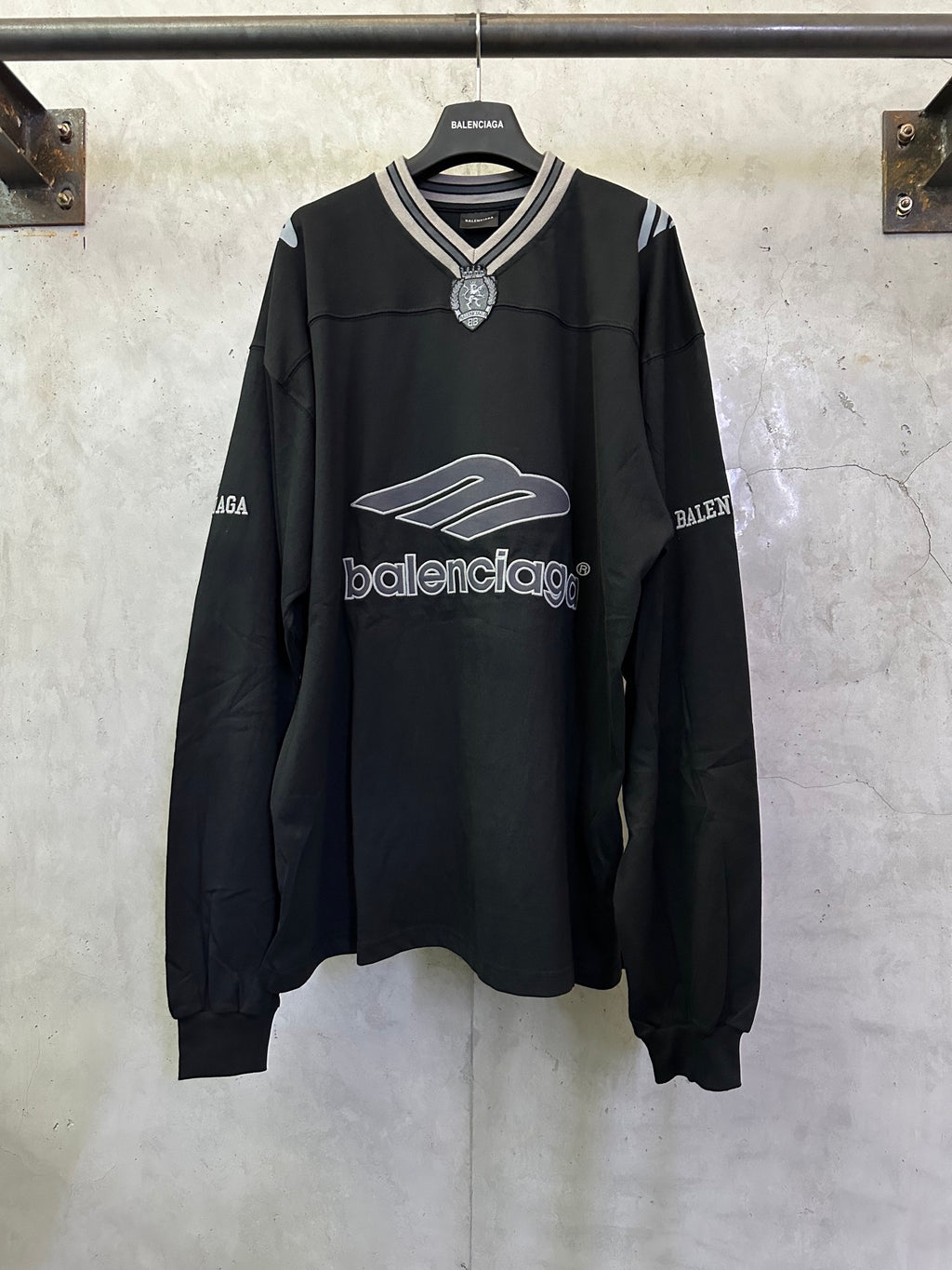 Black Balenciaga long-sleeve top with striped V-neck and crest charm at collar