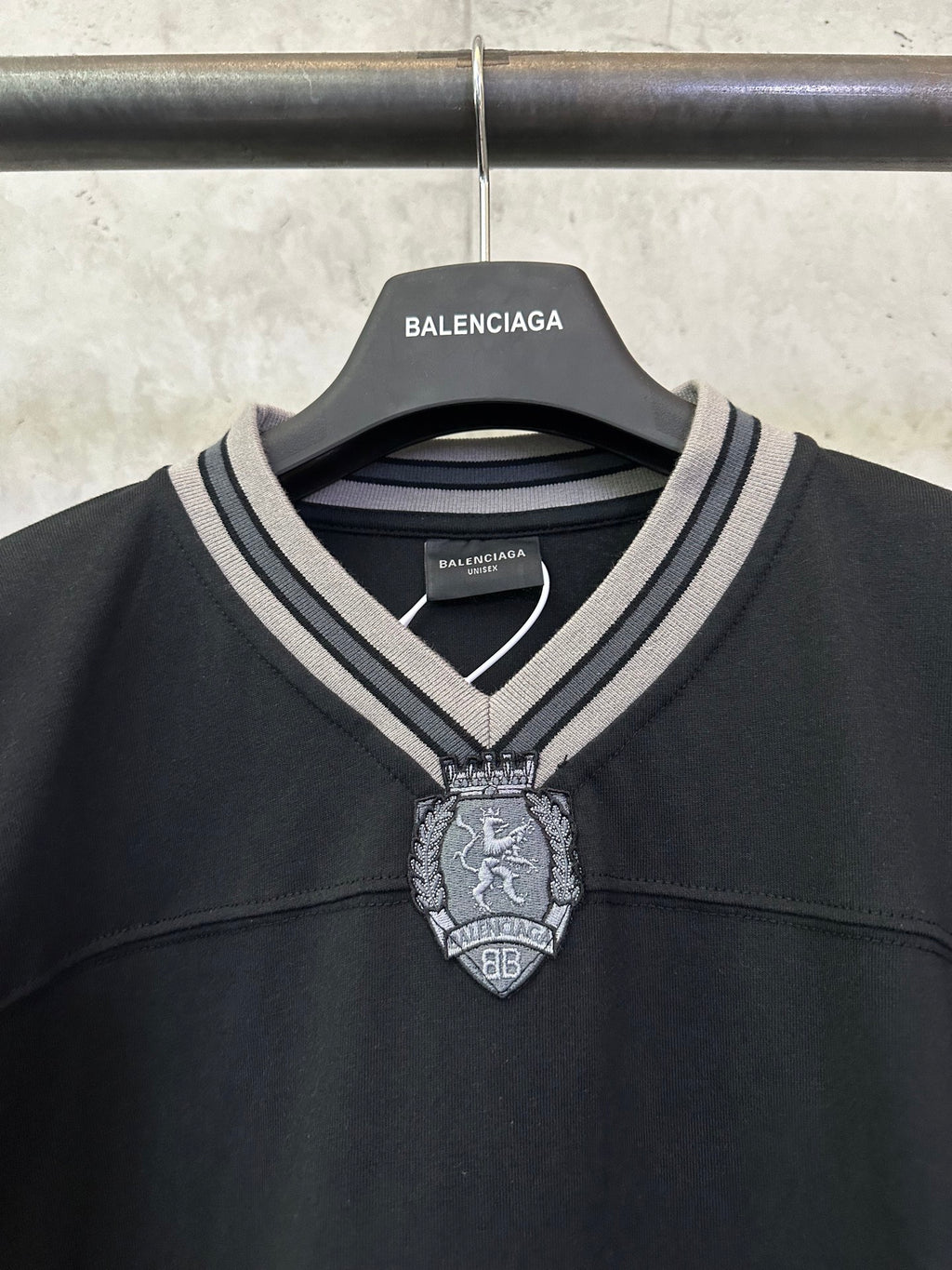 Black short-sleeve shirt neckline with striped V-trim and crest charm detail