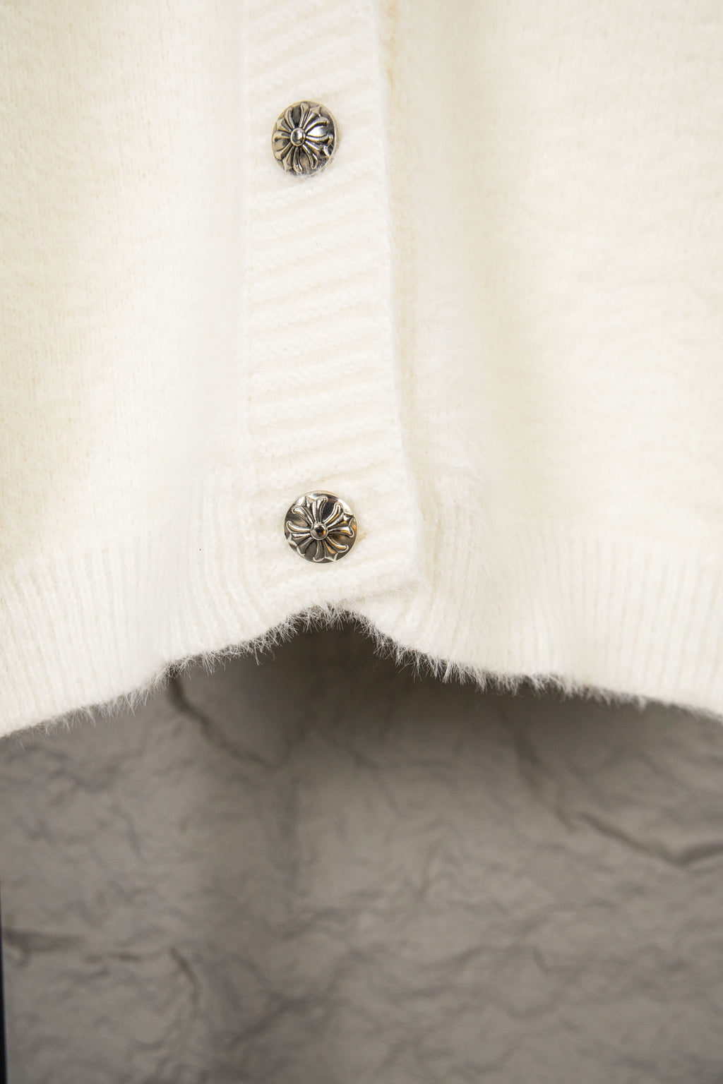 Cream knit cardigan with metal snap buttons on the lower front