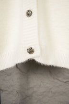 Cream knit cardigan with metal snap buttons on the lower front