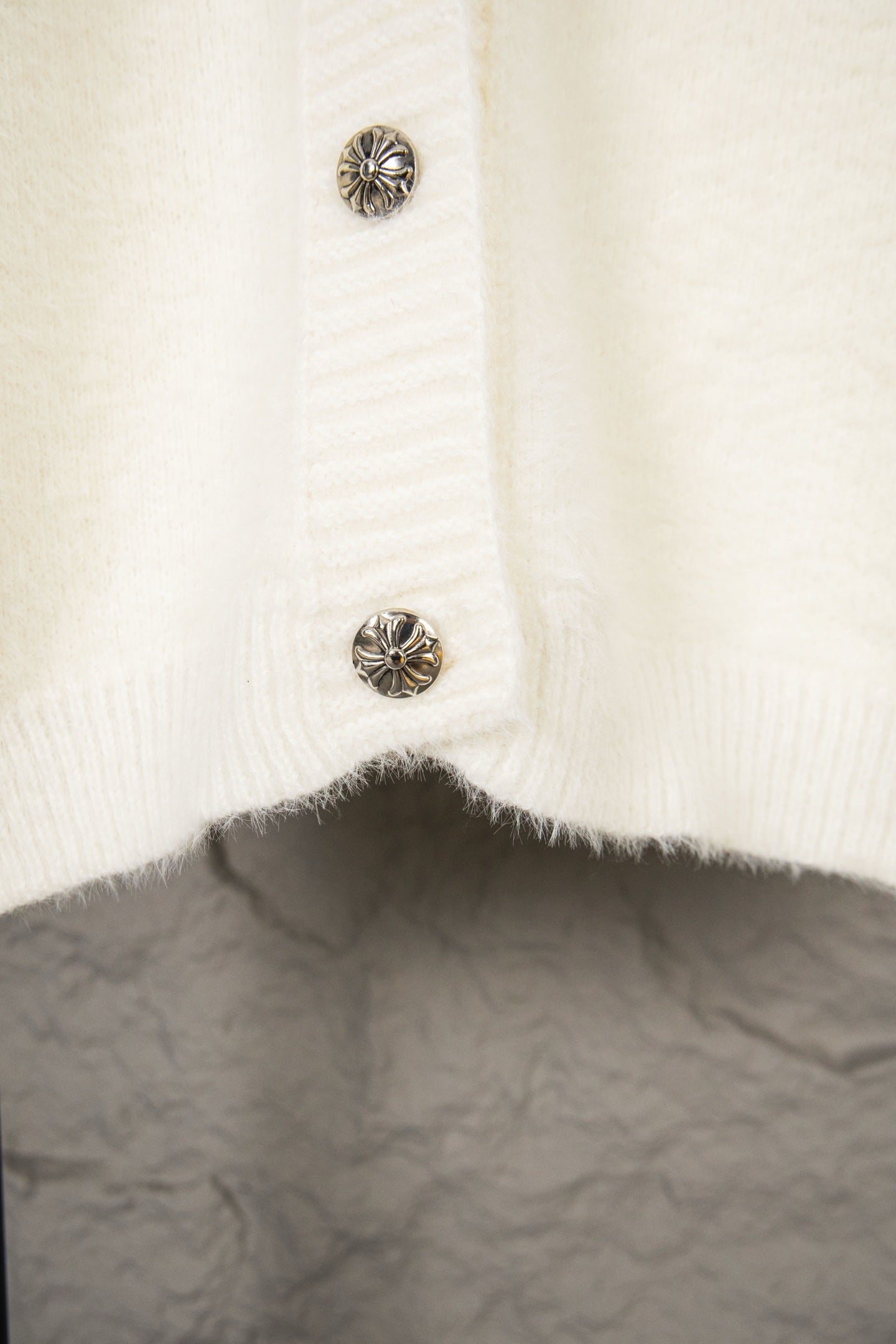 Cream knit cardigan with metal snap buttons on the lower front