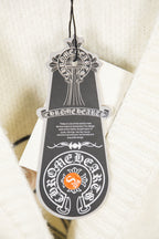 Cream knit cardigan product tag with decorative logo on hanging string