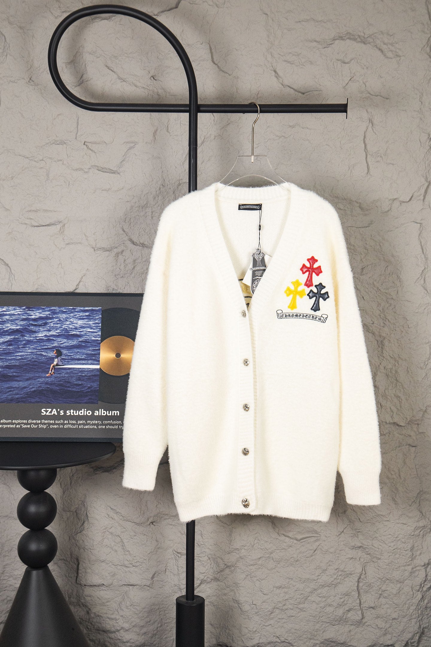 Cream fuzzy knit cardigan with button front and cross-and-flower emblem