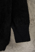 Black cardigan lower sleeve and hem close-up with textured knit