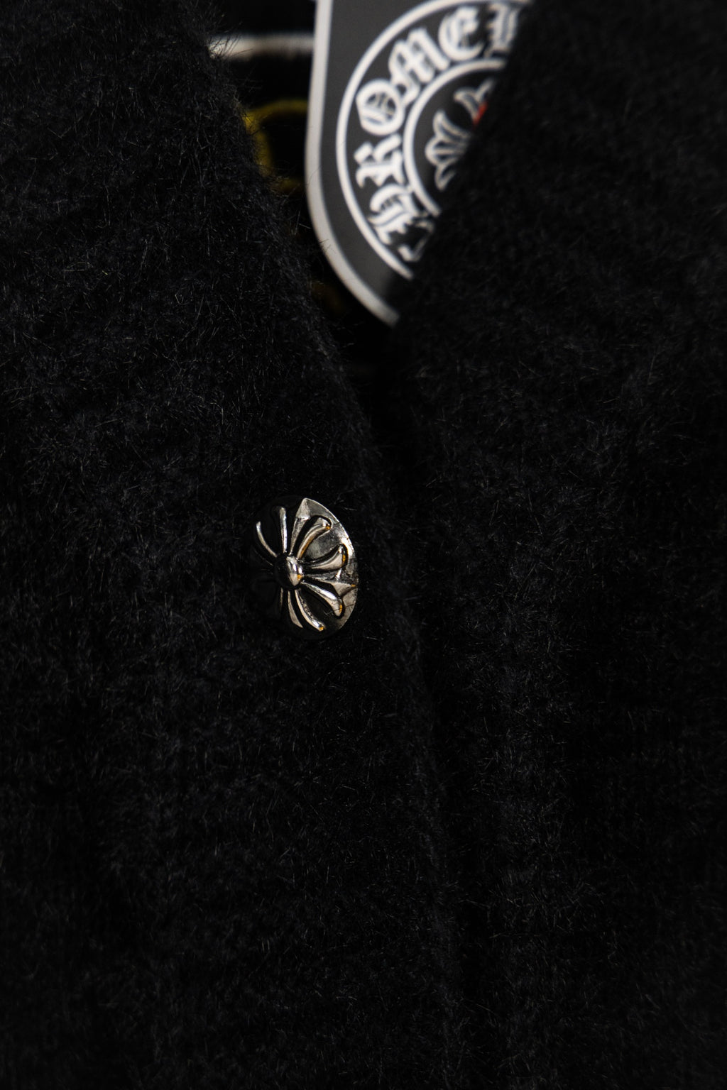 Black long garment with small chrome emblem detail