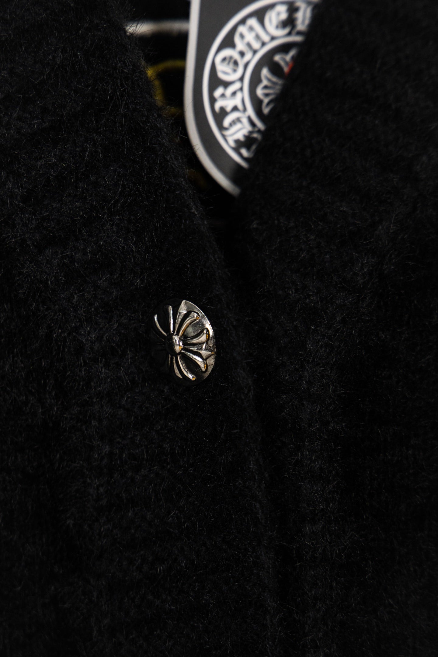 Black long garment with small chrome emblem detail