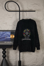 Black cardigan sweater on hanger with large round back emblem graphic