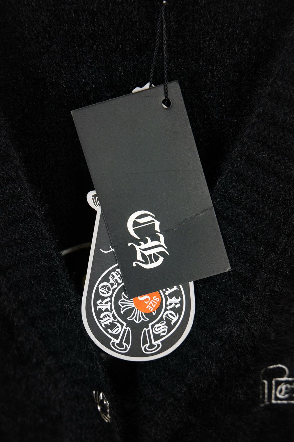 Black cardigan with attached gray hang tag showing white logo symbol