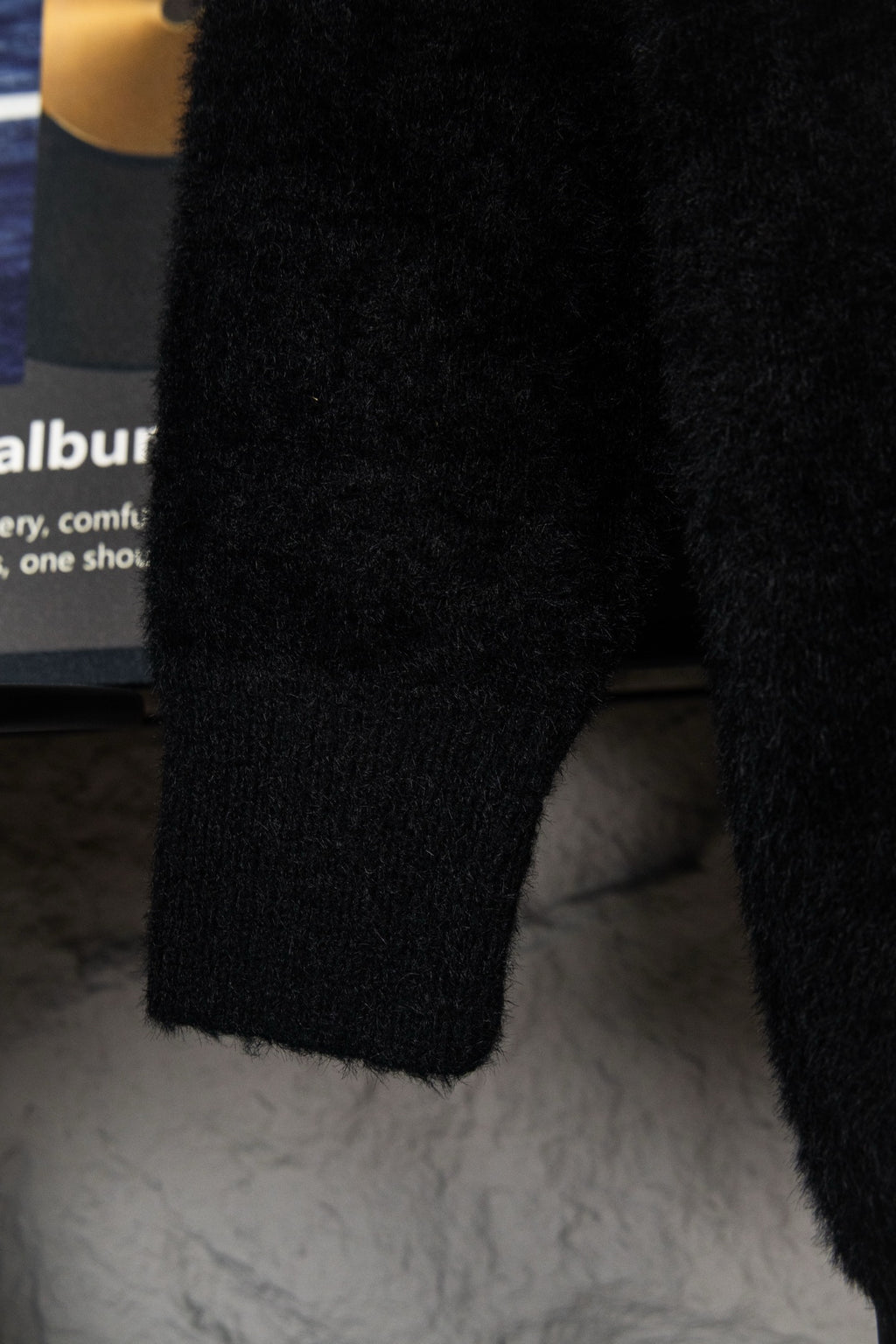 Black cardigan sleeve detail on hanger with fuzzy knit texture