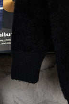 Black cardigan sleeve detail on hanger with fuzzy knit texture