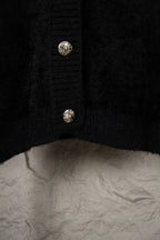 Black cardigan hem close-up with two small silver buttons