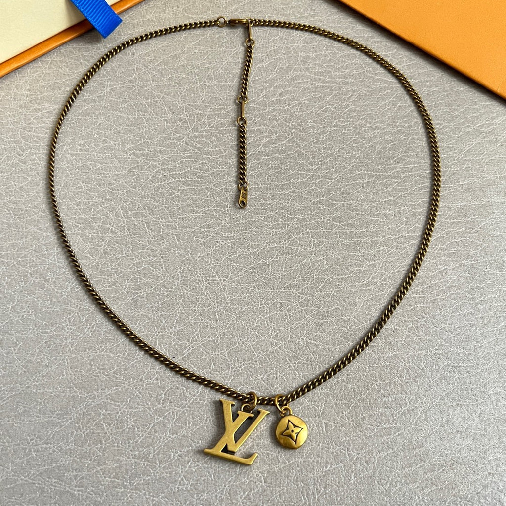 Gold-tone LV and star charm necklace with chain, laid on light fabric pouch